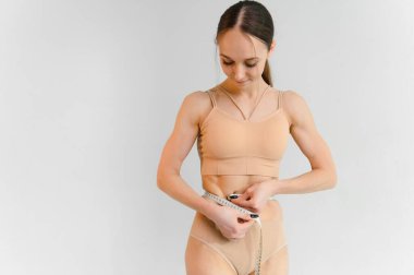 Flat stomach with measuring tape. Measuring a woman's waist with a measuring tape