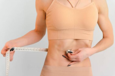 Flat stomach with measuring tape. Measuring a woman's waist with a measuring tape