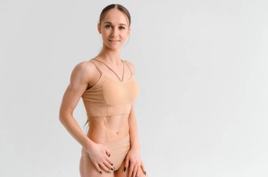 Şişirilmiş karın kaslarının görüntüsü. Stüdyoda beyaz arka planda poz veren güzel bir kadın. Fitness, vücut geliştirme, aerobik konsepti. Karışık ortam