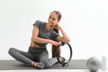 Fit young brunette pilates instructor showing different exercises on a white background a mat