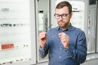 male client chooing new eyeglasses frame for his new eyeglasses in optical store.