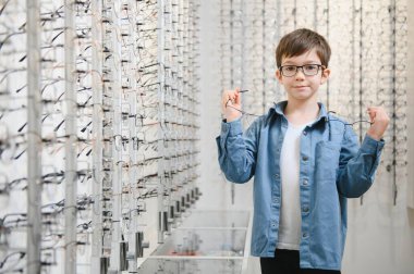 boy choosing glasses in optics store