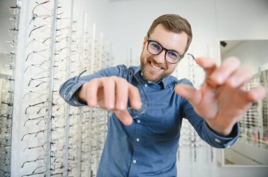 Shot of a handsome bearded man trying on new glasses at the eyewear store.Man buying glasses.Health, eyesight, vision, fashion, shopping.