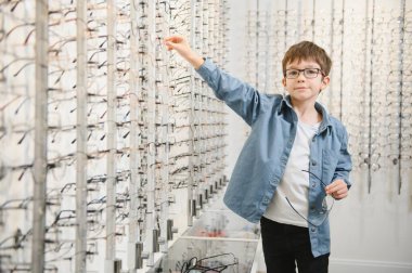 boy choosing glasses in optics store