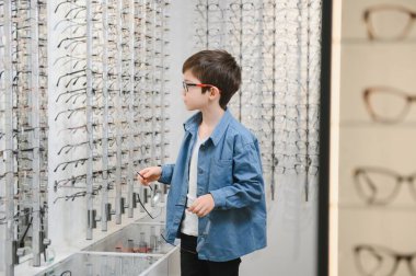 boy choosing glasses in optics store