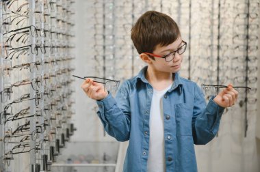 boy choosing glasses in optics store