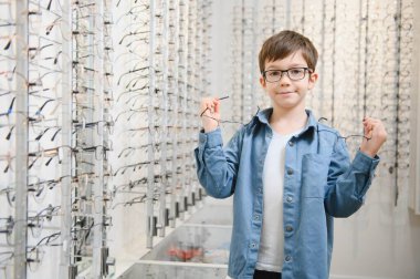 boy choosing glasses in optics store