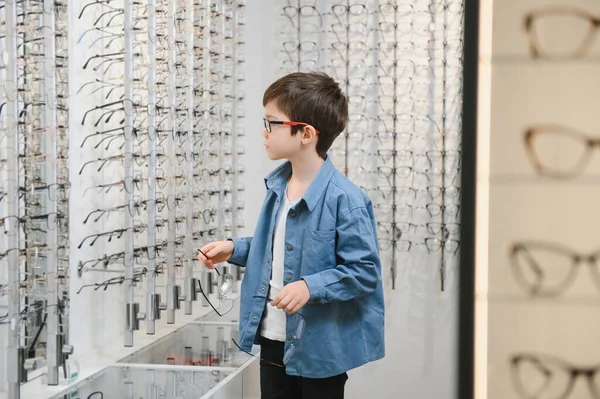 boy choosing glasses in optics store