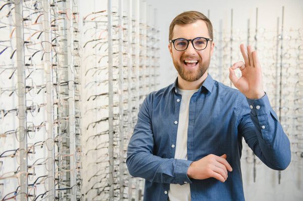 Shot of a handsome bearded man trying on new glasses at the eyewear store.Man buying glasses.Health, eyesight, vision, fashion, shopping.