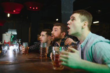 Group of excited friends in beer pub watching sports match.