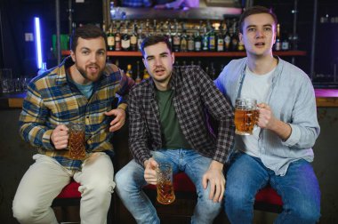 Group of excited friends in beer pub watching sports match.