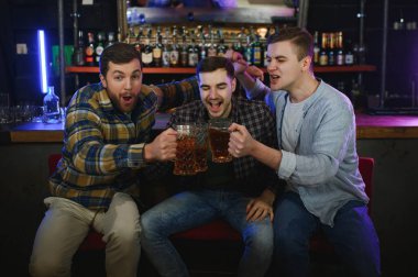 Group of excited friends in beer pub watching sports match.