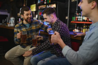 Friends resting in the pub with beer in hands. Having conversation