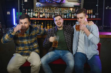 Group of excited friends in beer pub watching sports match.