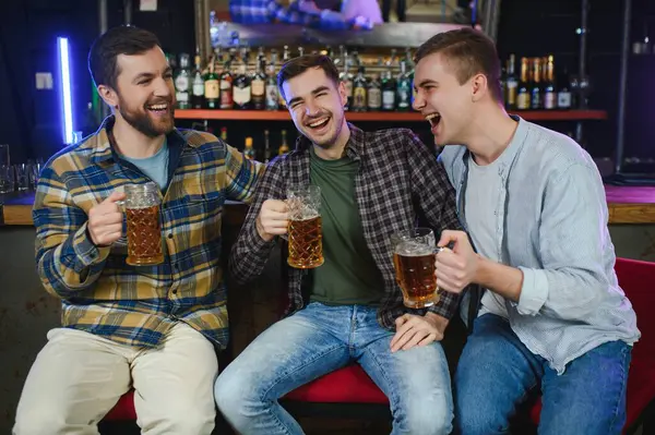 Friends resting in the pub with beer in hands. Having conversation