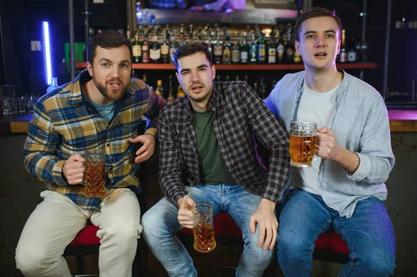 Group of excited friends in beer pub watching sports match.