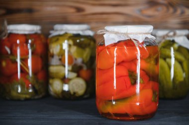 Canned cucumbers and tomatoes with craft lids on a wooden background. Cucumbers and tomatoes with place for text. Stocks of canned food. Harvest, stocks for the winter