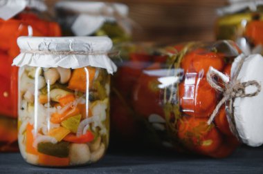 Canned cucumbers and tomatoes with craft lids on a wooden background. Cucumbers and tomatoes with place for text. Stocks of canned food. Harvest, stocks for the winter