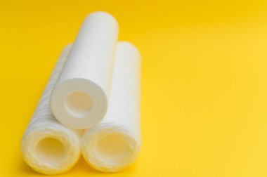 Su filtreleri. Karbon kartuşlar ve sarı arka planda bir bardak. Ev filtreleme sistemi.