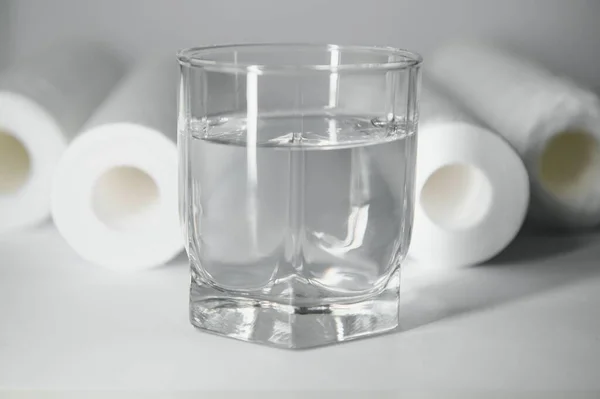 A glass of drink water and filter cartridges at white background.
