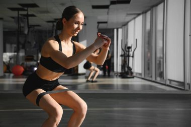 Crossfit healthy lifestyle concept. Nice chaming adorable beautiful sporty muscular fitness model lady wearing sports panties and top with black elastic band on legs muscles doing sit-ups.