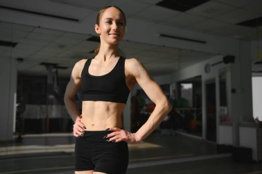 Image of a beautiful strong happy cheerful young sports woman posing at gym.