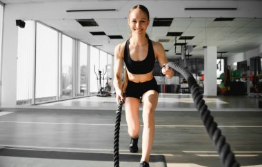 Bir kız oynarken spor salonunda spor malzemeleri - bir ip kullanarak egzersizleri yapıyor