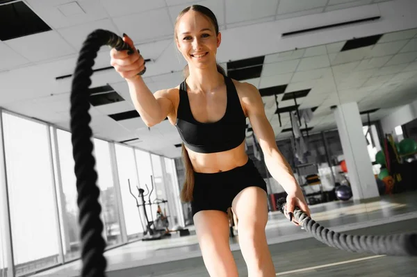 Woman training with battle ropes in gym.