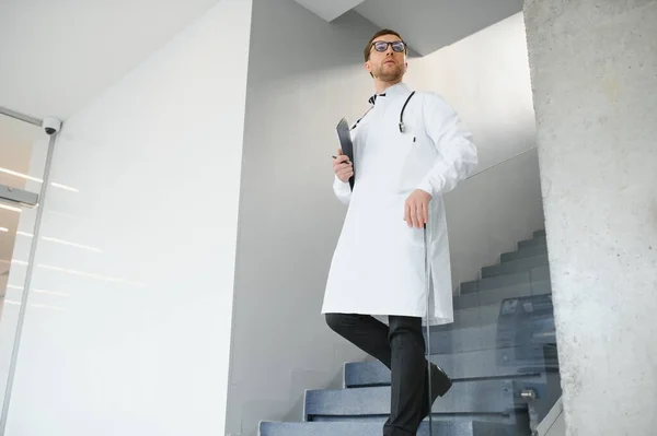 Doctor with stethoscope on stairs in hospital. Space for text.