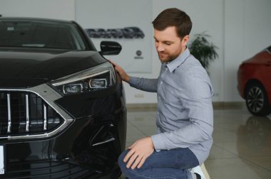 Genç adam yeni bir araç içinde araba Bayilik seçmektir
