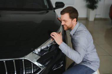 Genç adam yeni bir araç içinde araba Bayilik seçmektir