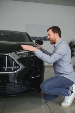 Genç adam yeni bir araç içinde araba Bayilik seçmektir
