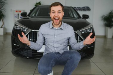 Genç adam yeni bir araç içinde araba Bayilik seçmektir