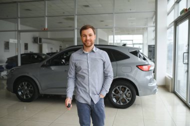 a man chooses a new car for himself walks between the rows in a car dealership.