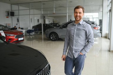 a man chooses a new car for himself walks between the rows in a car dealership.