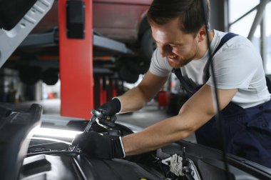 Tamirci tamirhanede araba motoru üzerinde çalışıyor. Onarım servisi