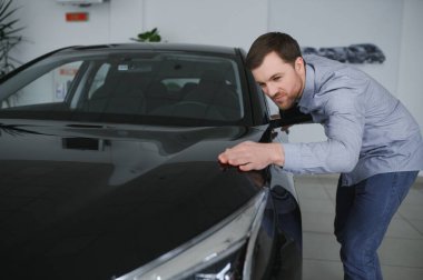 Genç adam yeni bir araç içinde araba Bayilik seçmektir