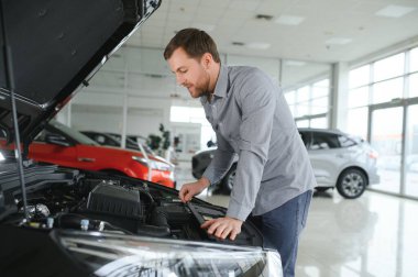 Genç adam yeni bir araç içinde araba Bayilik seçmektir