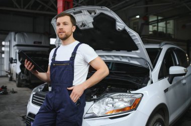 Otomobil bilgisayar teşhisi. Araç tamircisi, araç hizmet atölyesindeki teşhis ekipmanlarında motor arızası arıyor.