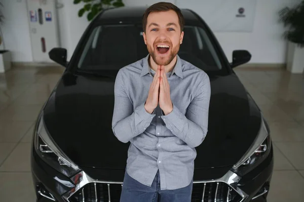 stock image Visiting car dealership. Handsome bearded man is stroking his new car and smiling.