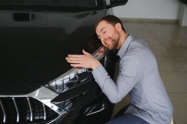 Genç adam yeni bir araç içinde araba Bayilik seçmektir