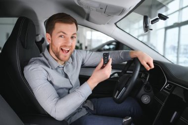 Successful and happy. Shot of a happy mature man smiling to the camera sitting in his brand new car at the local dealership.