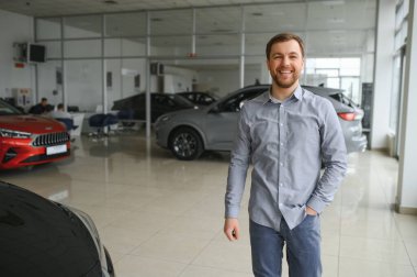 Araba galerisini ziyaret ediyorum. Yakışıklı sakallı adam yeni arabasını okşuyor ve gülümsüyor.