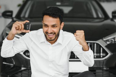 Closeup portrait happy, smiling, young man, buyer showing keys of his new car.