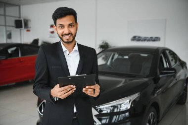 indian cheerful car salesman at showroom