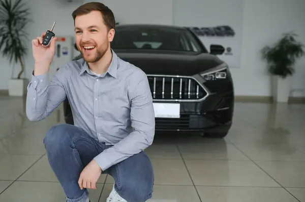 stock image Yes, that's my new car. Customer in car dealership. Young man with keys in hand