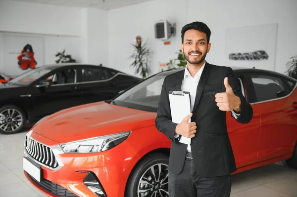 Successful indian businessman in a car dealership - sale of vehicles to customers