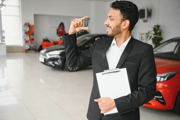 Indyjski Wesoły Sprzedawca Samochodów Pokazując Nowy Samochód Salonie — Zdjęcie stockowe