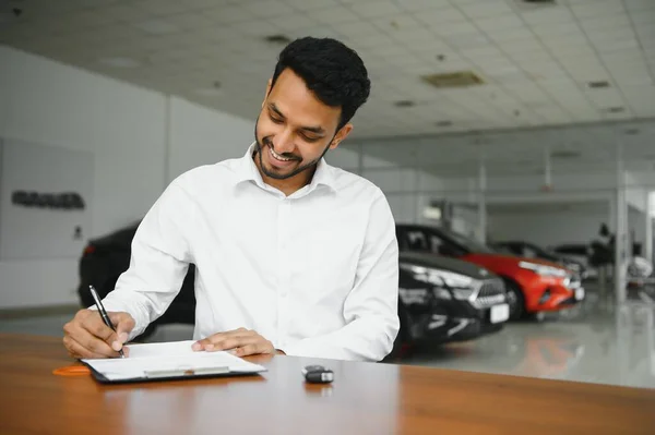 Young Indian Man Signing Documents Car Dealership — Stockfoto