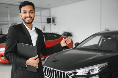 indian cheerful car salesman at showroom